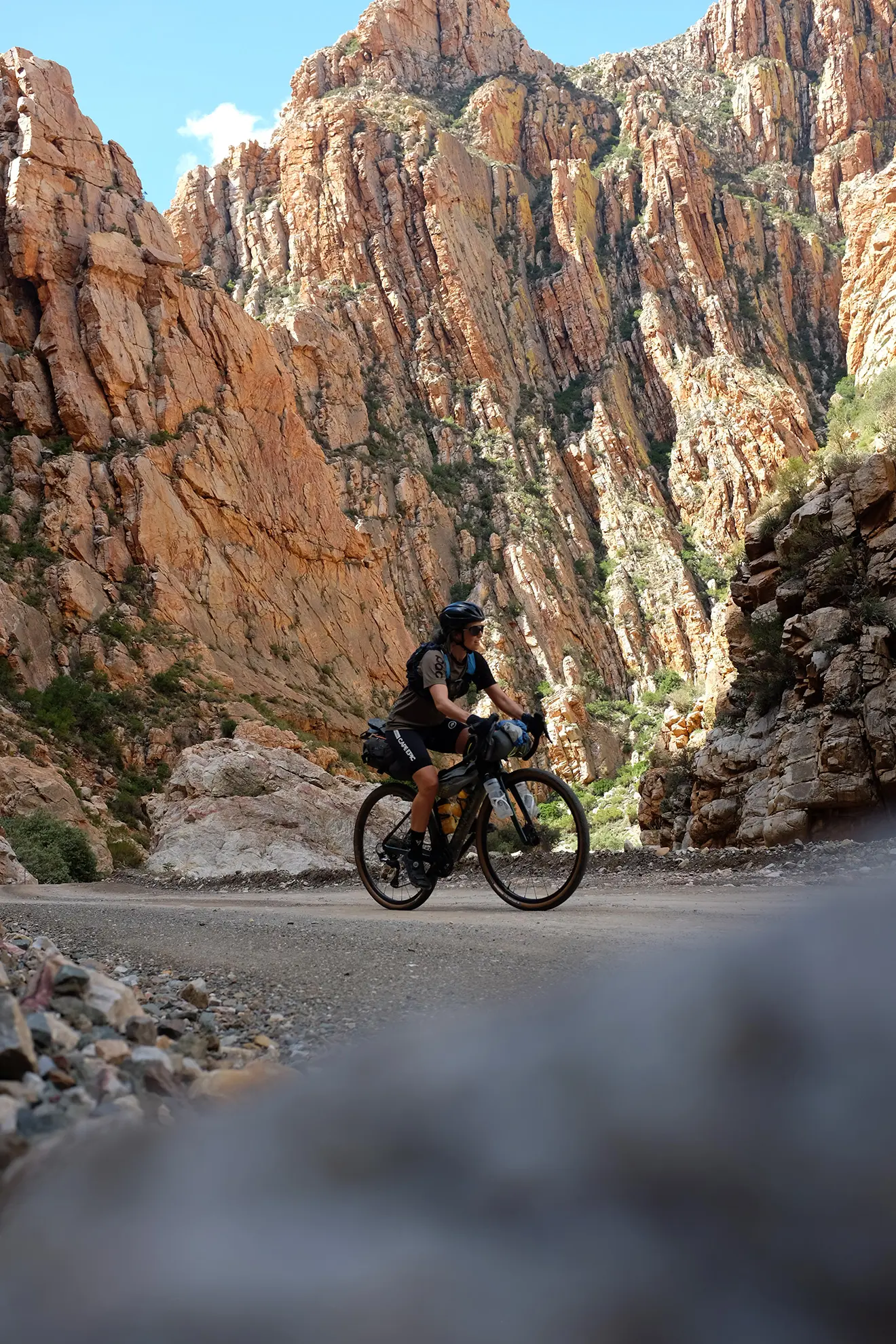 A cyclist bikepacking through the towering rock canyon of the Swartberg Pass, Western Cape